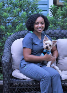 a member of the Animal Medical Center veterinary team sitting with a cute dog in her lap